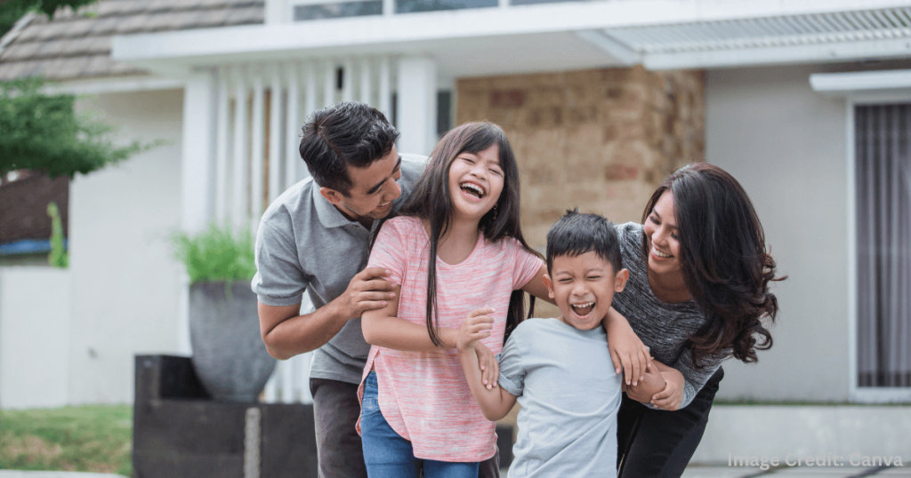 행복하게 웃으며 집 앞에서 가족과 시간을 보내는 부모와 두 자녀 (Happy Family Spending Time Together in Front of Their Home)
